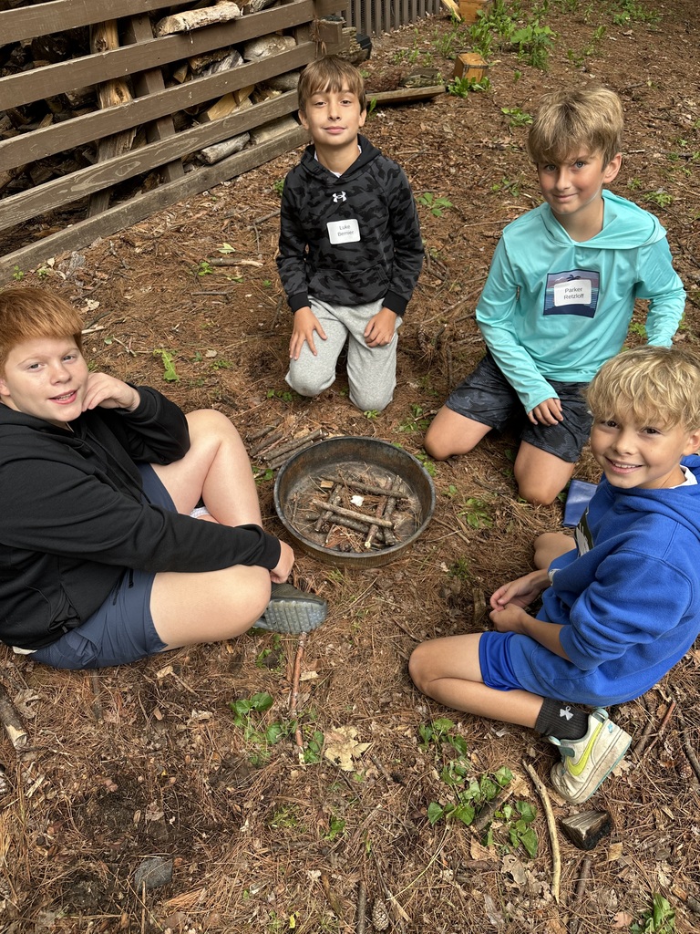 Four middle school students around an "outdoor fire building challenge".