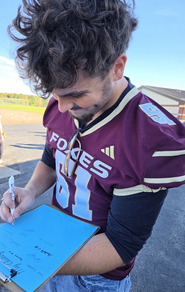 High school student signing autographs on a clipboard.