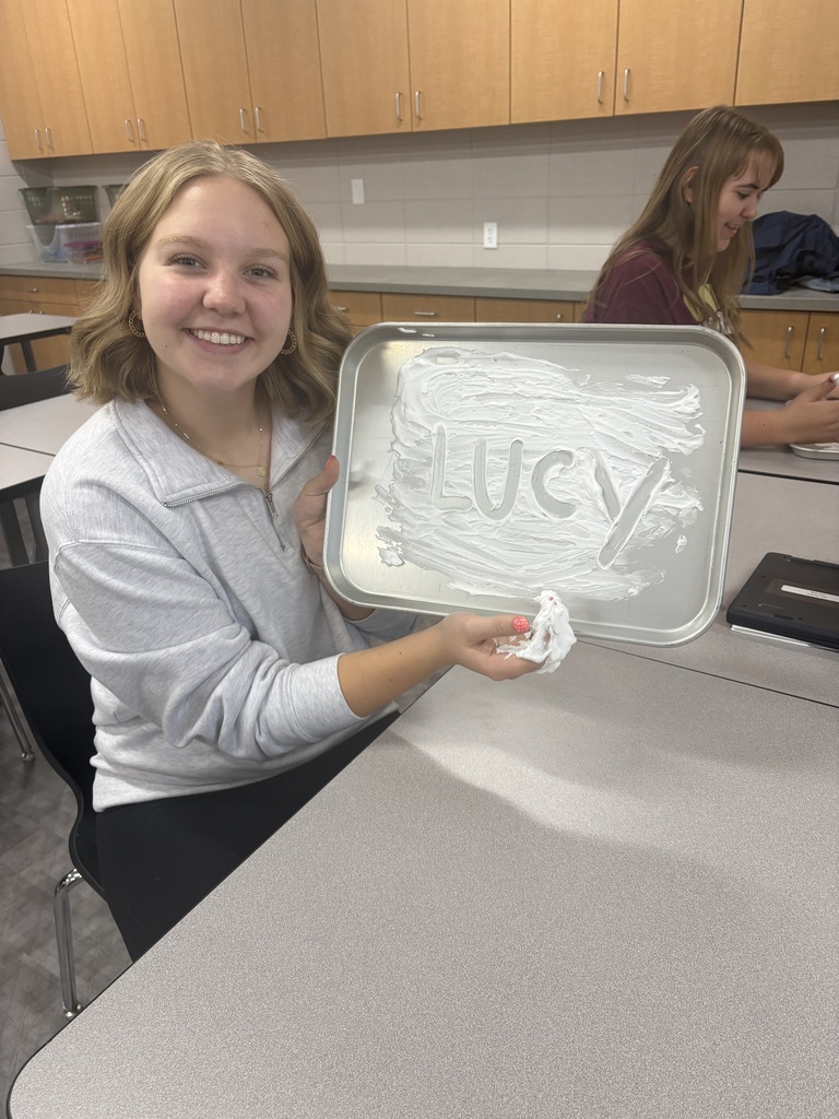 A high school student drawing their name in shaving cream in a tray.
