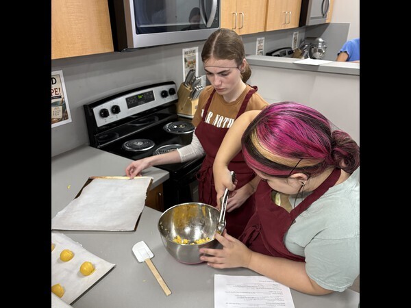 High school students putting cookie dough on a tray.