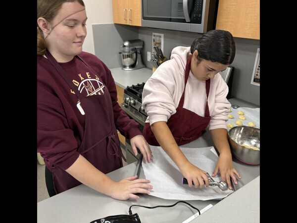 High school students putting cookie dough on a tray.