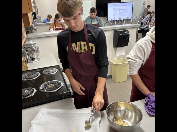High school students putting cookie dough on a tray.