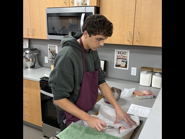 High school students putting cookie dough on a tray.
