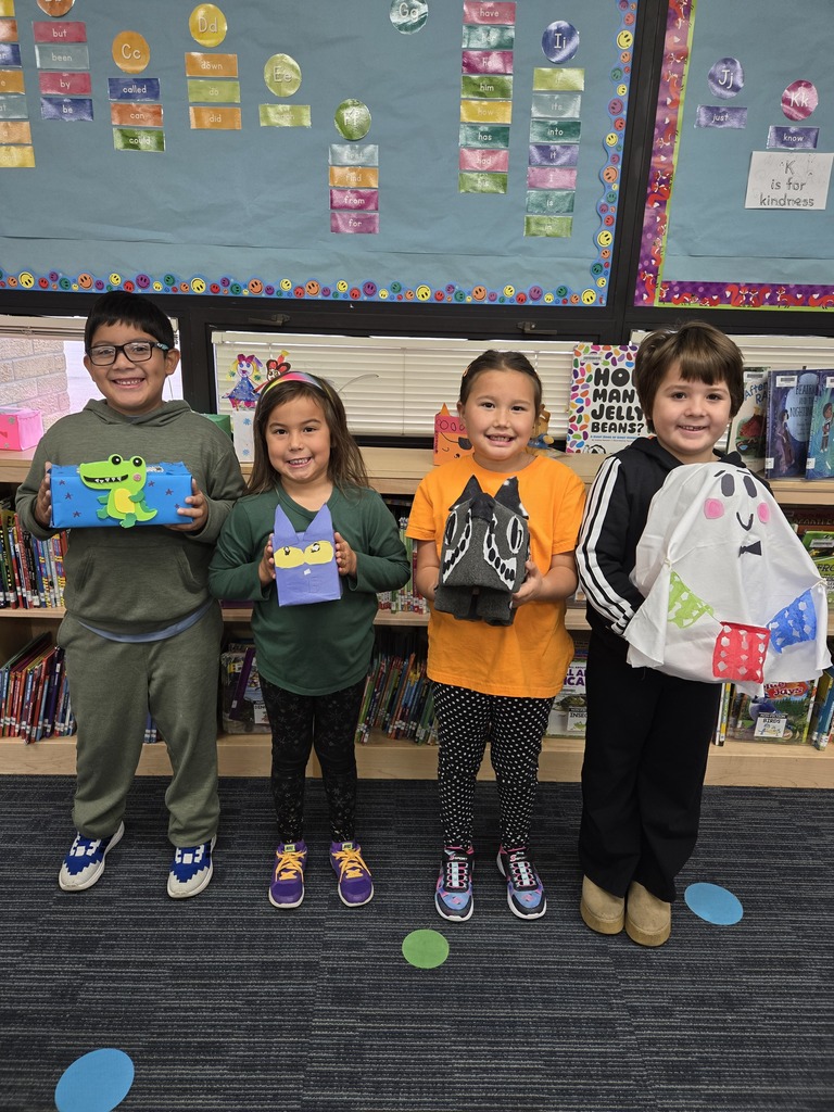 Early elementary students holding tissue box covers they created. 