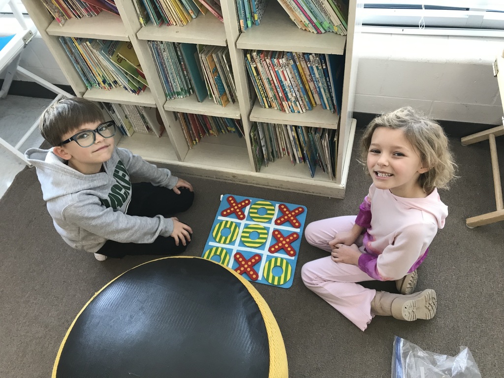 Elementary students playing tic-tac-toe on a large board.