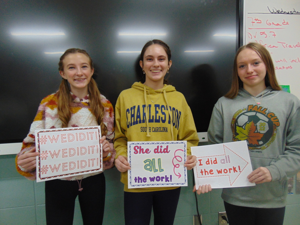 Three students holding signs after completing an Escape Room