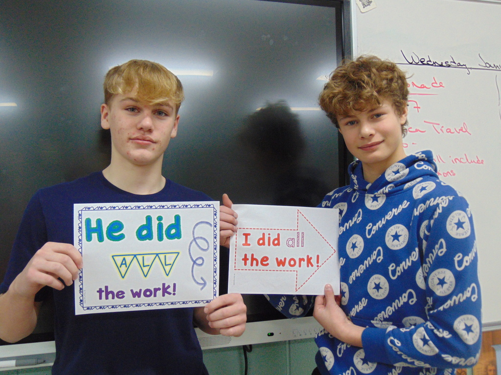 2 students holding signs after completing an Escape Room.
