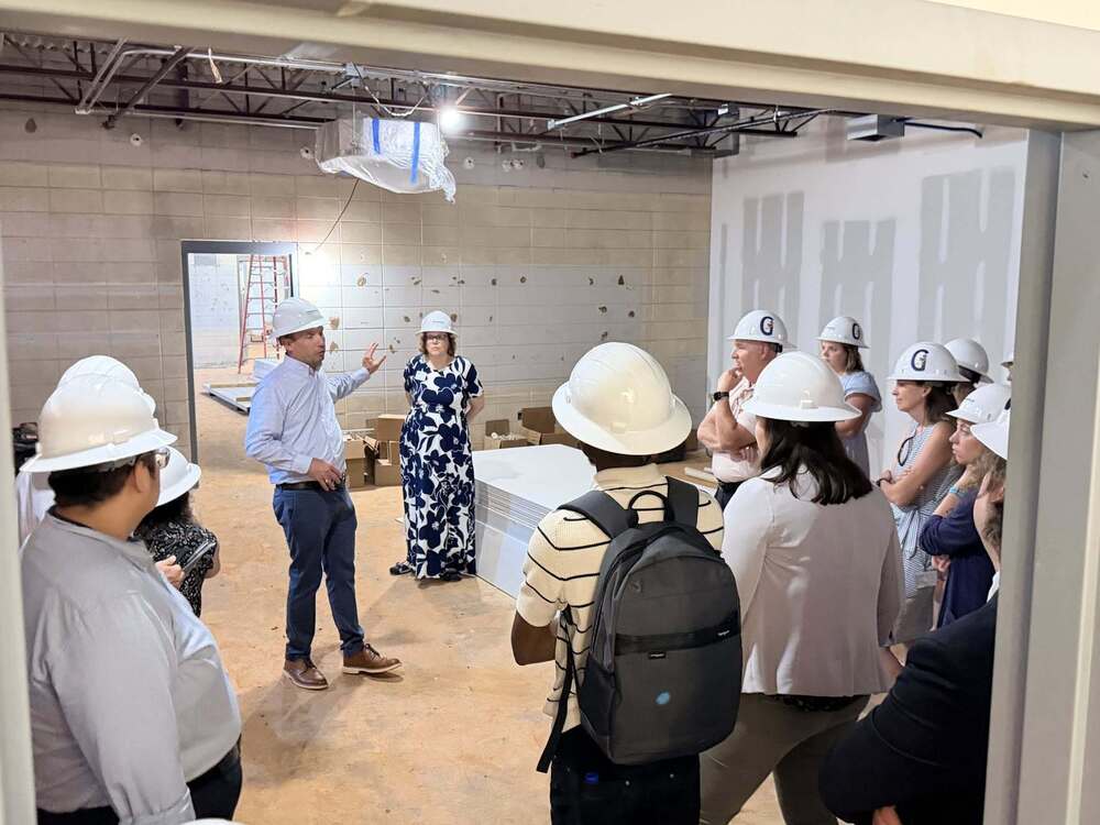 Large group inside of G2i.  All are wearing hard hats.  Tim Johnson, G2i Director is speaking to the group.