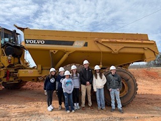 G2i Director with students in front of dump truck