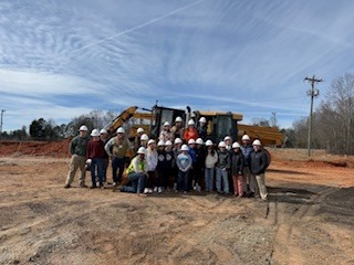 Group Photo at G2i site with bulldozer