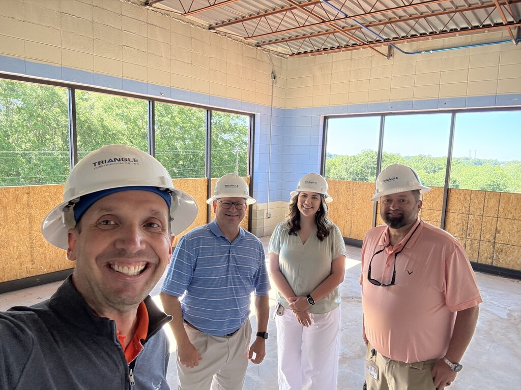 Tim Johnson, Ray Farley, Emily Brazinski, and Jeromy Arnett posing in G2i in front of two large windows.