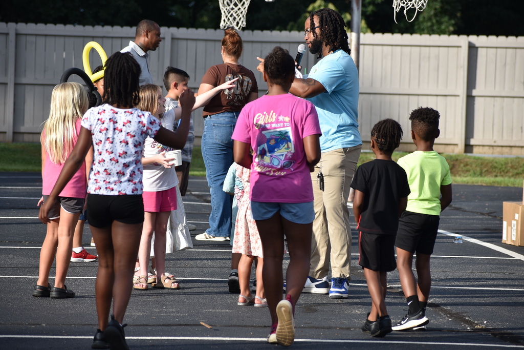 The image is of principal Danny Hall interacting with students on the blacktop outside. 