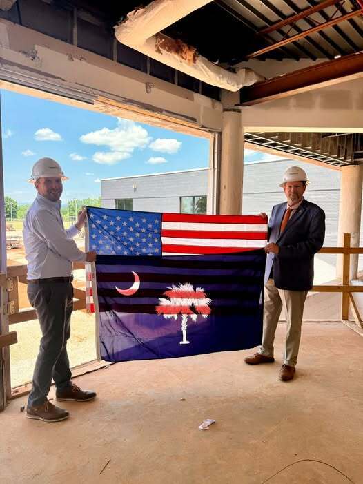 Tim Johnson and Rep Phillip Bowers holding an American and South Carolina Flag between them. 