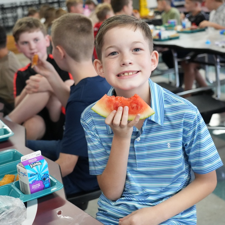 student eating watermelon at lunch