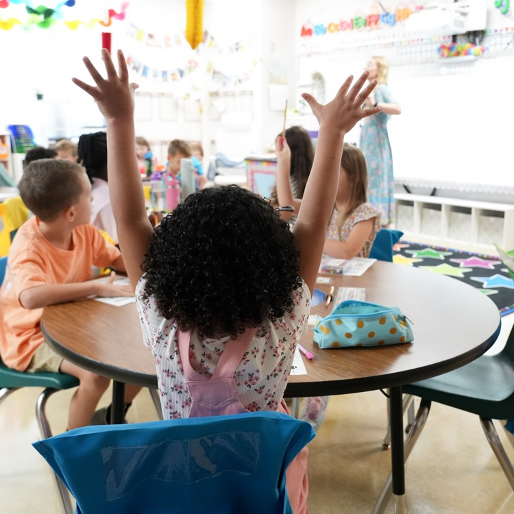 student raising hands in classroom