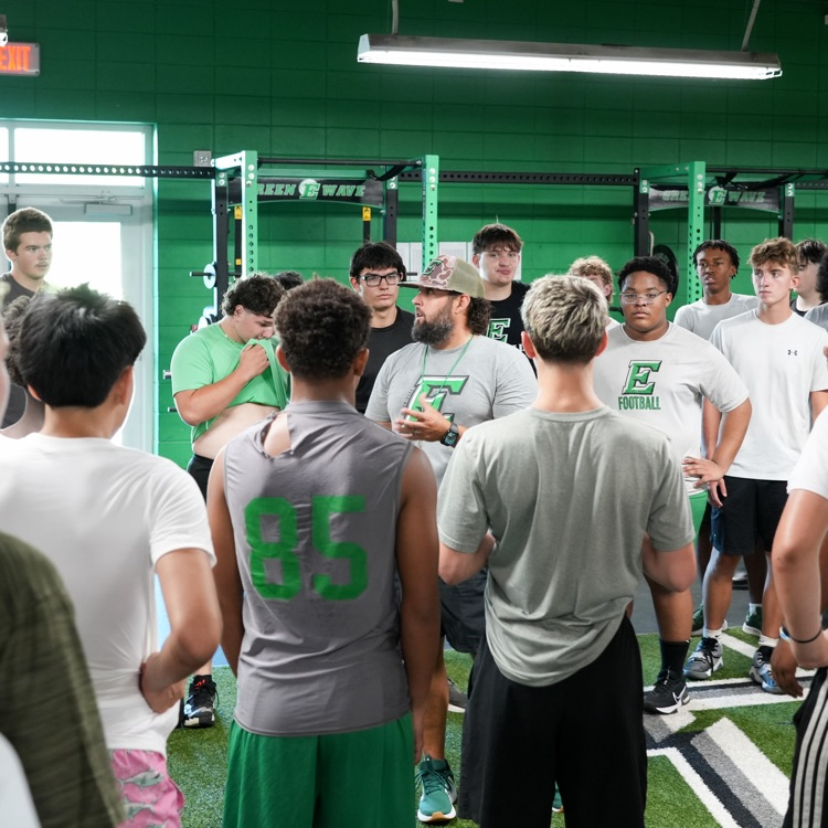 football coach and student athletes in huddle in weight room