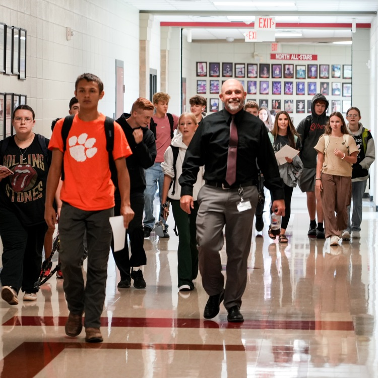principal walking with students in hallway