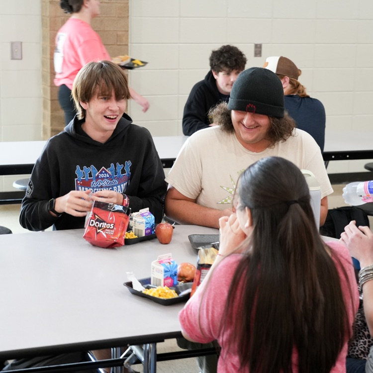 A group of students laughing while eating at lunch