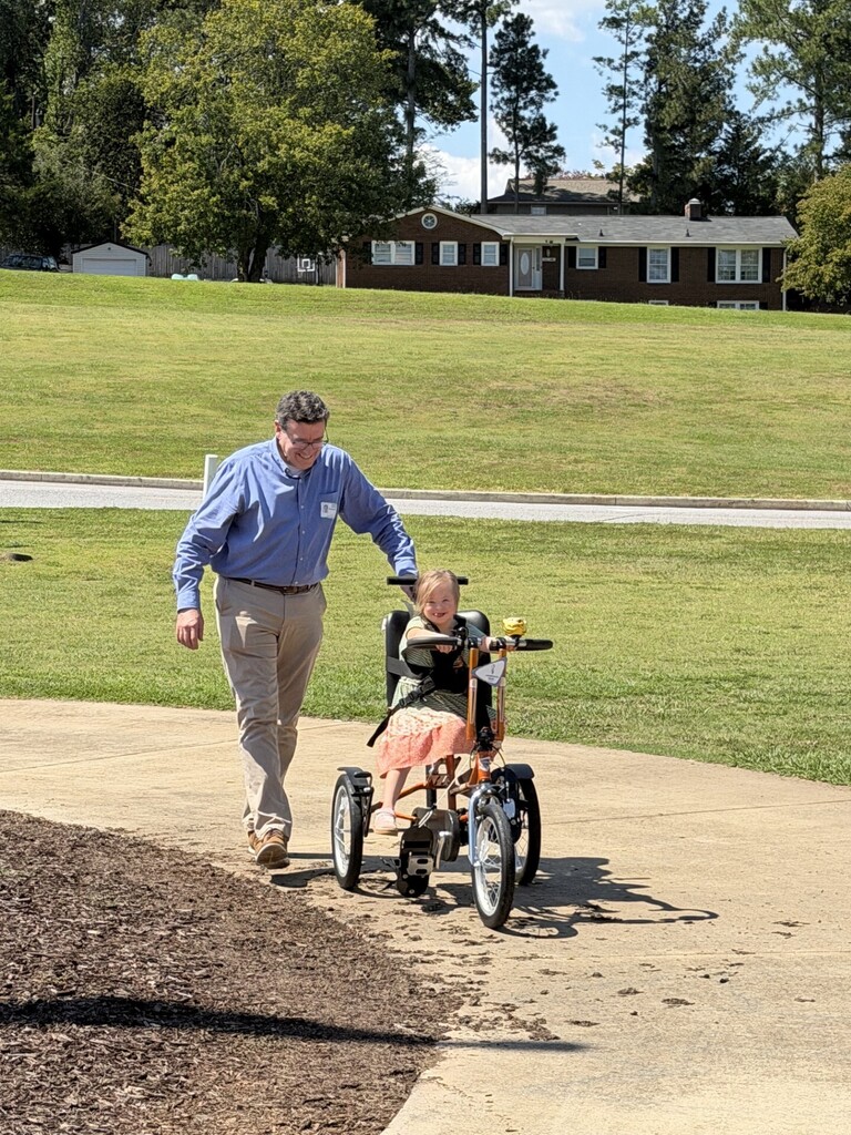 Student riding adaptive bike with Rotary representative
