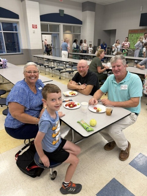 Student with grand guests enjoying fruit and donut holes