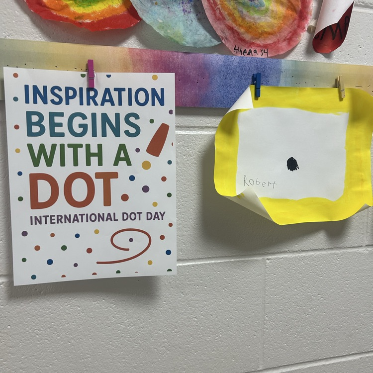 A “Make Your Mark” International Dot Day sign displayed beside a student’s bright yellow and black dot-inspired artwork.
