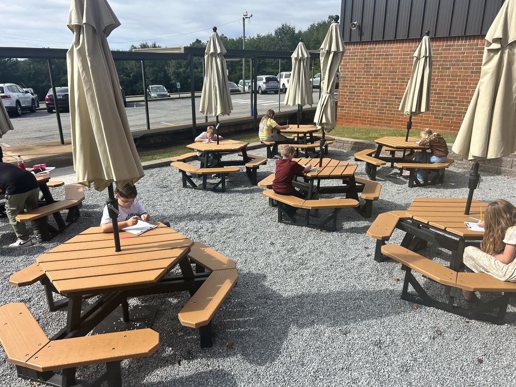 Fifth grade students participate in a writing activity and Roll and Read word game outdoors.
