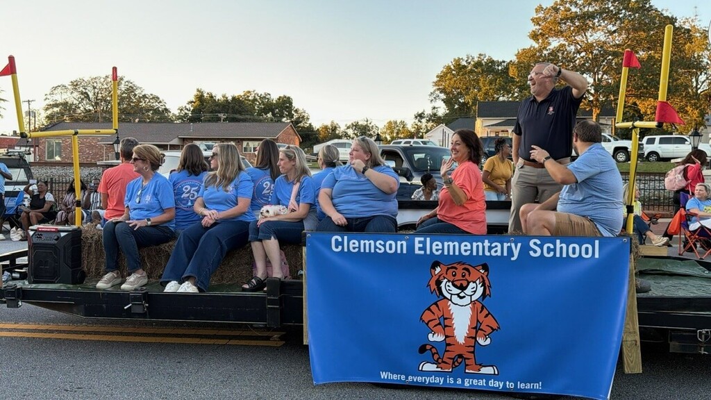 Teachers waving and smiling at students and former students in the Homecoming parade