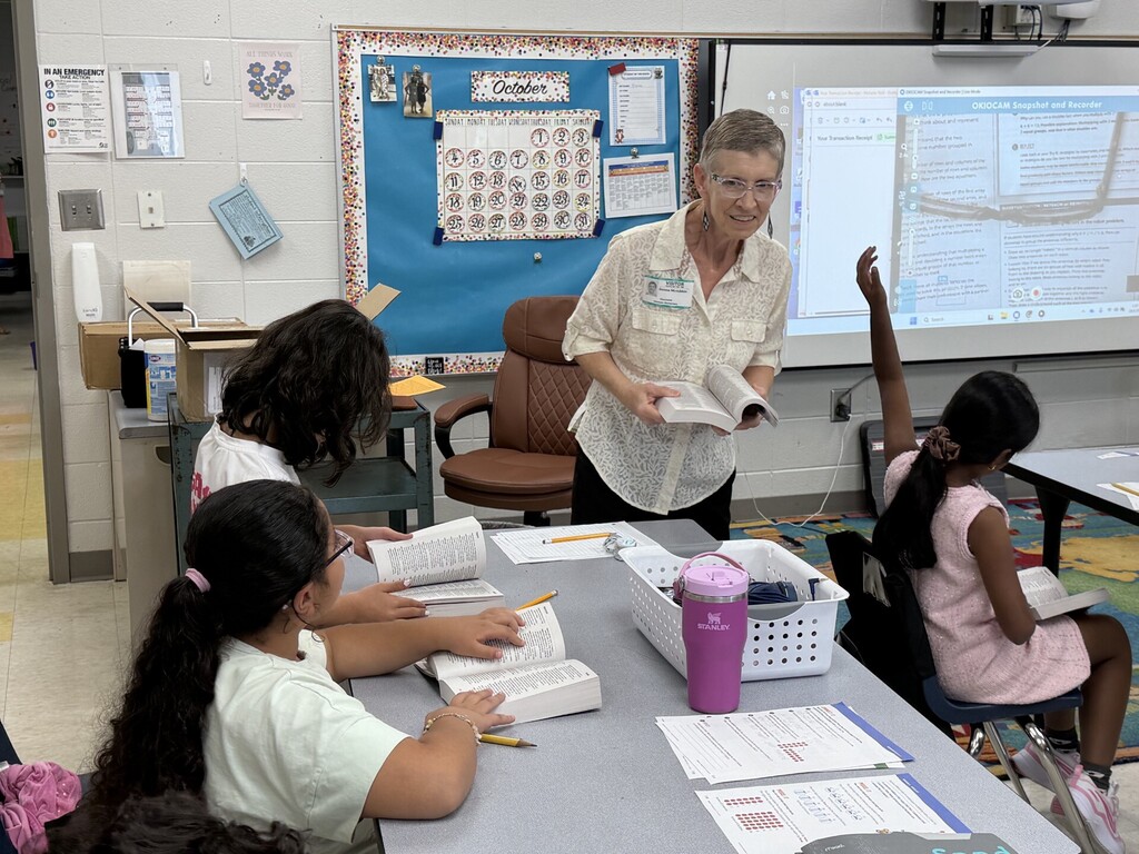Students working with a Rotarian to look up words.