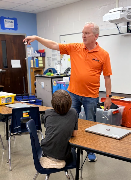 Mr. Mac teaching a student about using the lego robotics program to build a machine with a motor they can program
