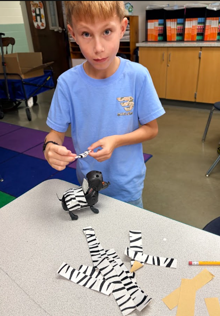 Student learning about the purpose of animal fur and covering his robotic dog with pretend fur