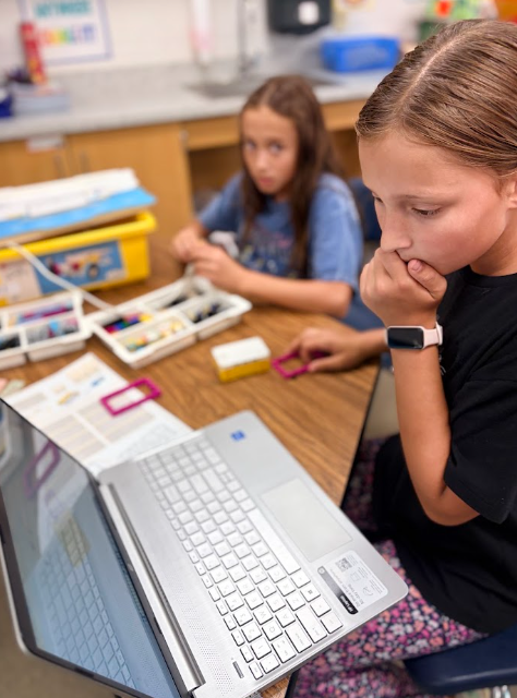 Two students using the lego robotics program to build a machine with a motor they can program