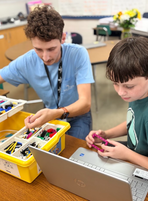 Two students using the lego robotics program to build a machine with a motor they can program