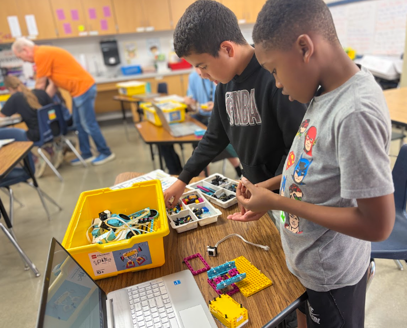Two students using the lego robotics program to build a machine with a motor they can program