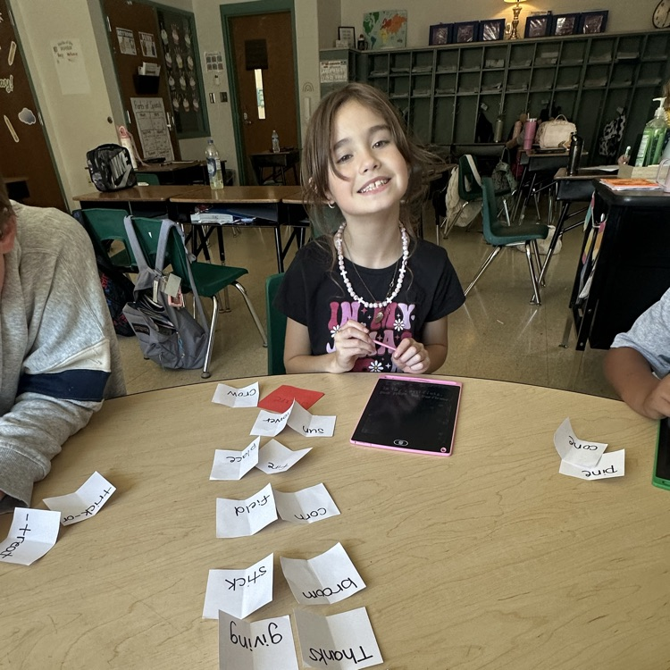 A smiling third grade student in Ms. Bezy’s class holds a stylus while working on a writing tablet during a hands-on compound word activity.