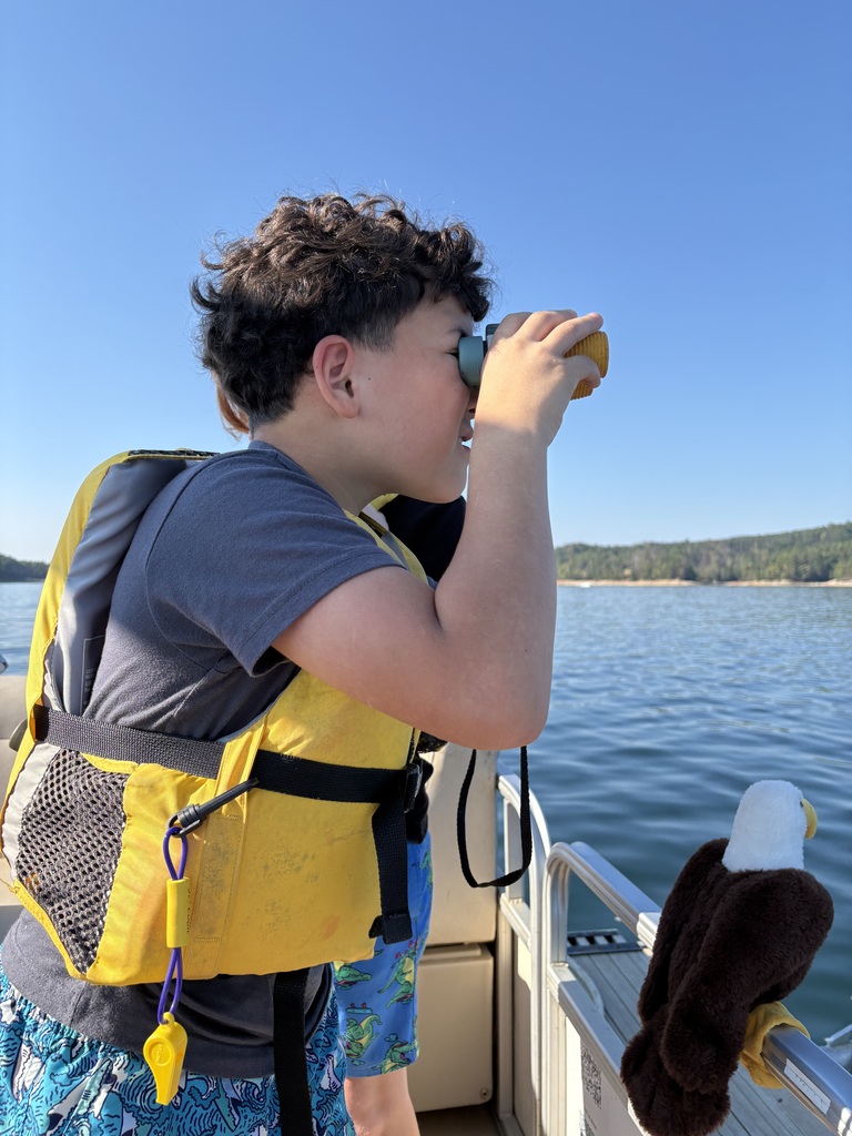 a student uses binoculars to look out on the lake