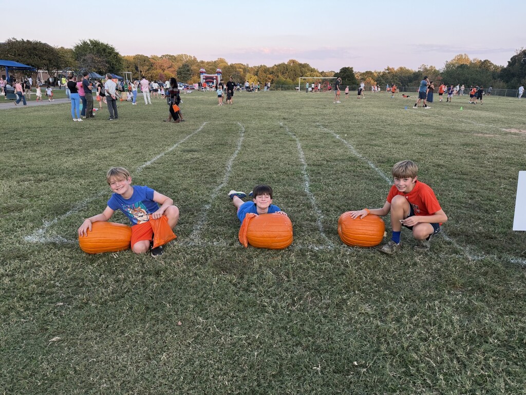 Students participating in a pumpkin rolling contest at the Fall Festival.