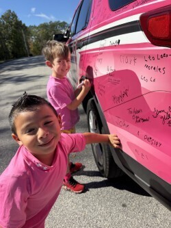 students sign the pink car