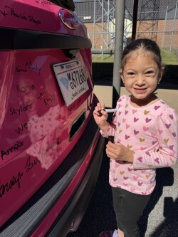 student signs the pink car