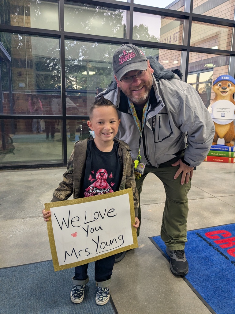 student poses with Officer Young and a sign