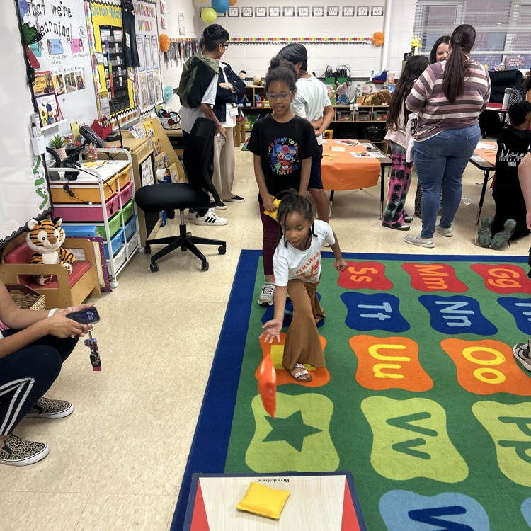 two students playing corn hole at family night 
