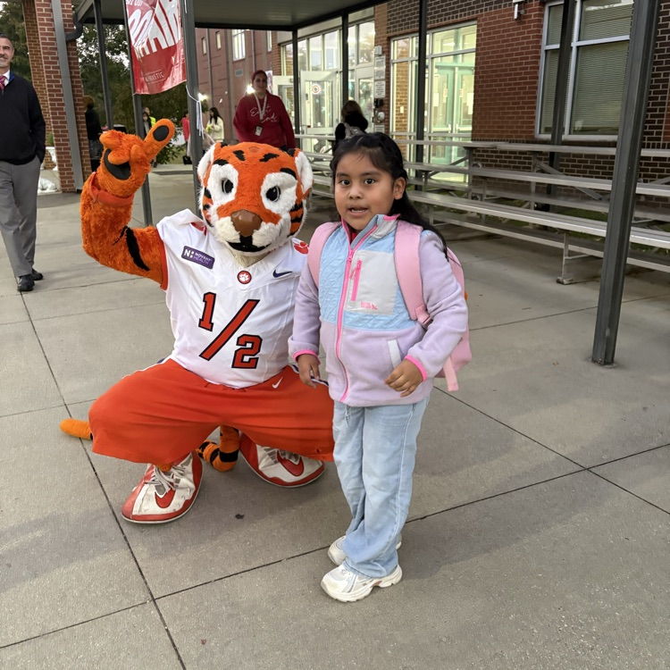 The Tiger Cub holding up the peace sign with a young bulldog in the car line at East End