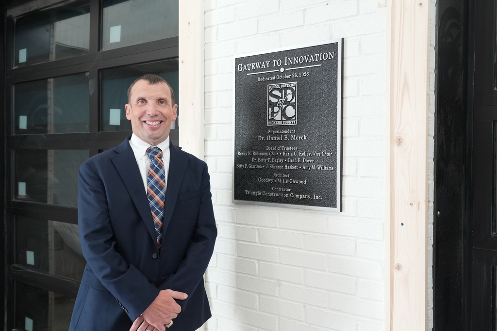 G2i Director Tim Johnson, posing with dedication plaque in lobby of G2i