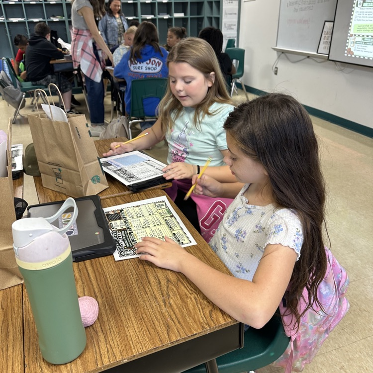 Two fifth grade girls with Starbucks menu adding together the ingredients for their drinks.