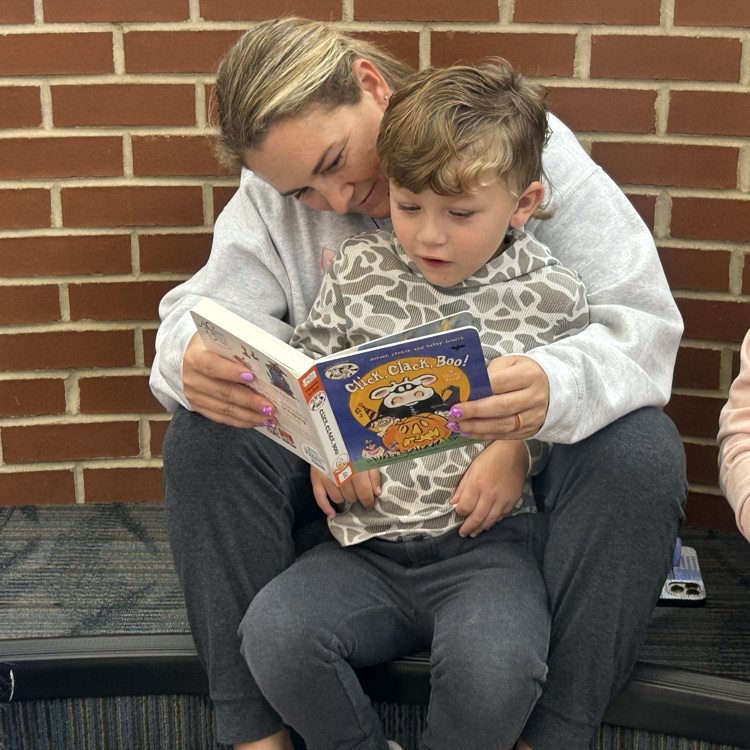 A parent and child reading a book during pup tales
