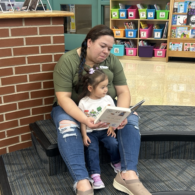 A parent and child reading a book during pup tales