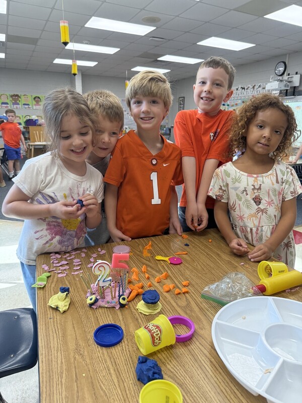 Kindergarten students making a 25th birthday cake at the Play-Doh  classroom center.