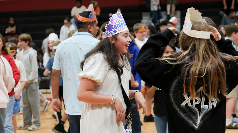 Student laughing and dancing with friends at Hispanic Heritage assembly