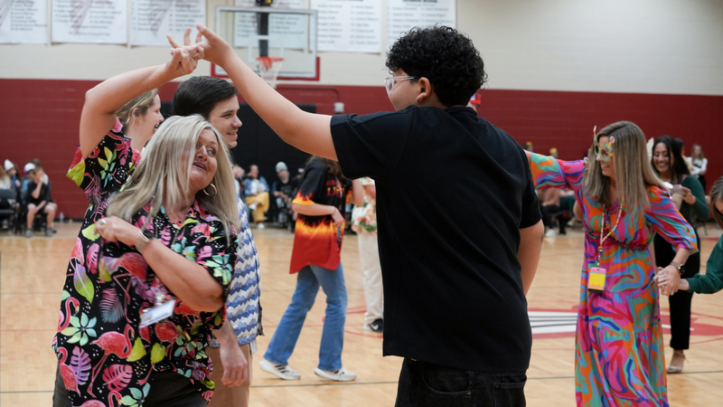 Student dancing with teacher at Hispanic Heritage assembly
