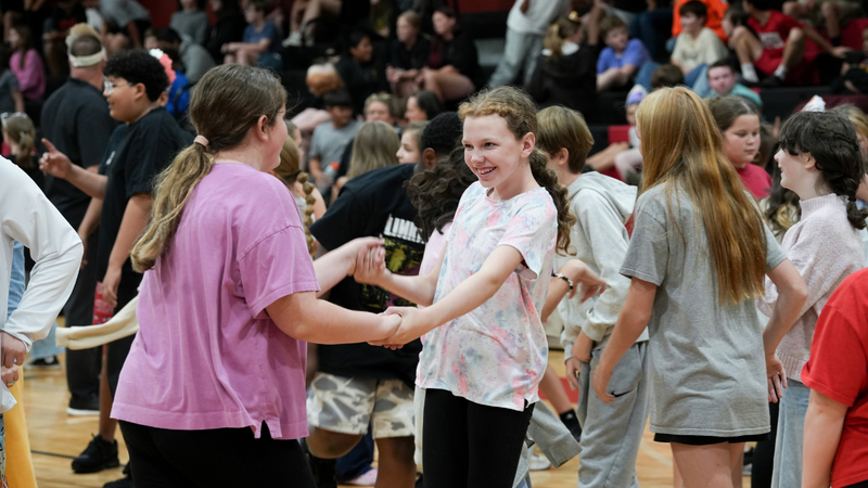 Two students smiling as they dance together at Hispanic Heritage assembly