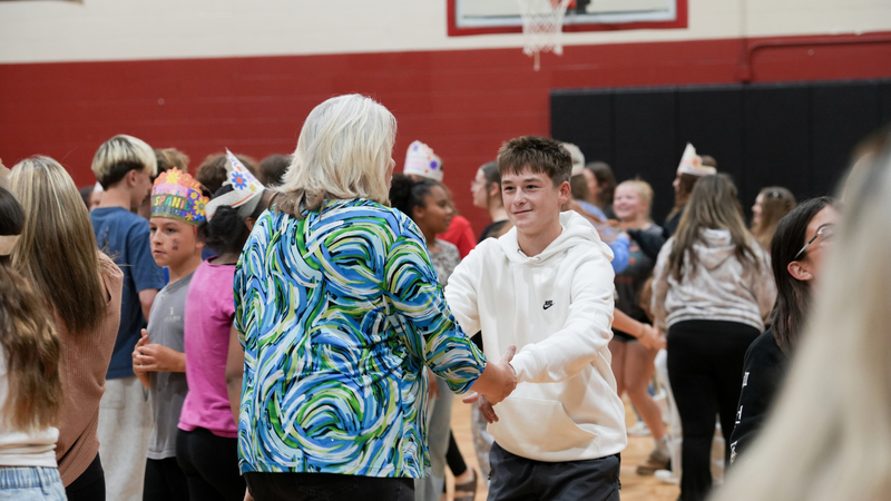 Student dancing with teacher at Hispanic Heritage assembly